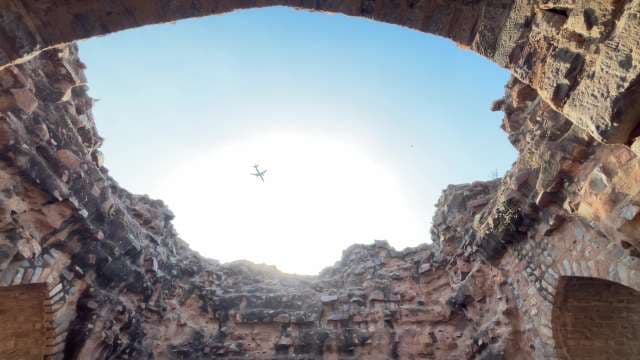 Airplane Flying Over Ancient Ruins at Sunrise