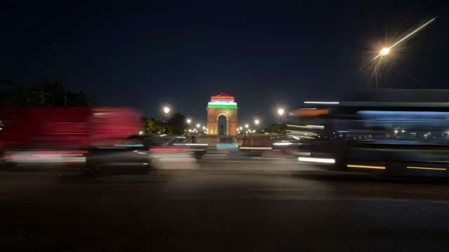 India Gate Illuminated at Night With Bustling Traffic