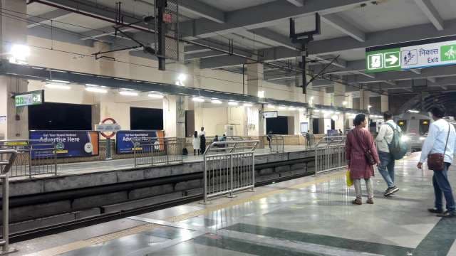 Commuters Await Train Arrival at Delhi Metro Station