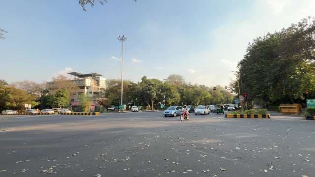 Busy Urban Intersection With Cars, Bikes, and Trees in Delhi