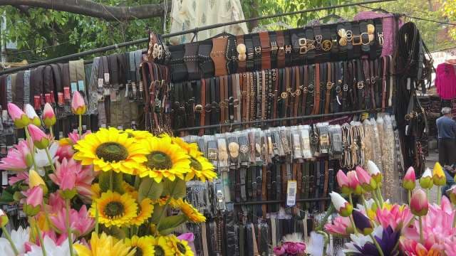 Colorful Street Market Stall Displaying Belts and Flowers