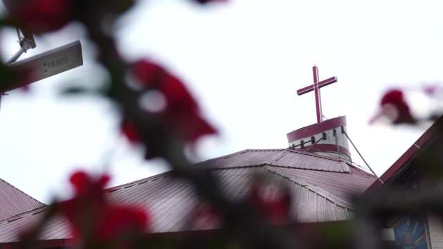 Red Cross Atop Church Roof Framed by Blossoms