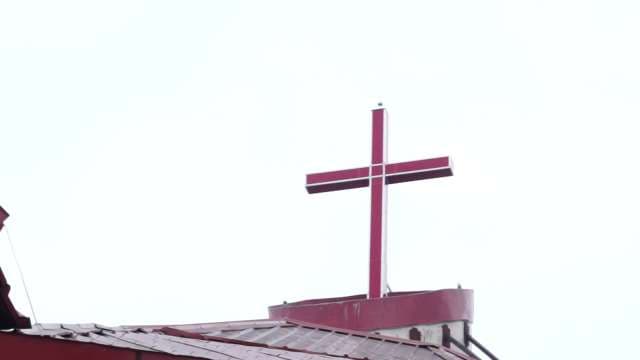 Red Church Cross on Rooftop Against Bright Sky