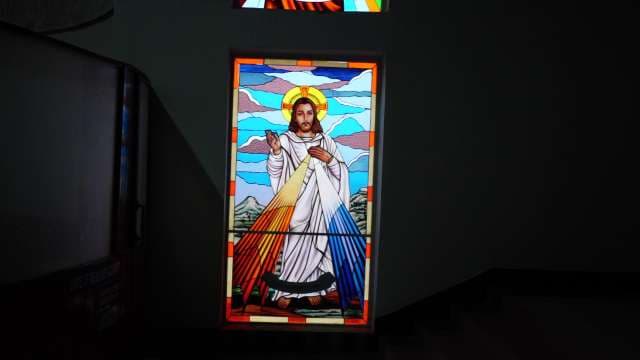 Stained Glass Jesus Window Illuminated in Church Hallway