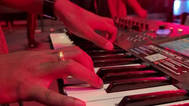 Professional Musician Performing on Keyboard with Red Stage Lighting