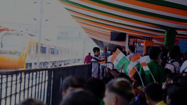 Patriotic Crowd Waving Indian Flags at a Decorated Railway Station