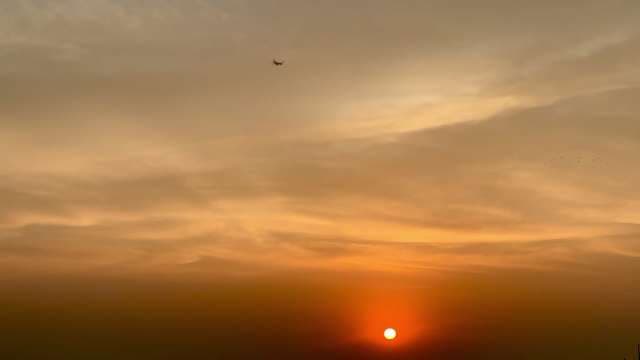 Beautiful Golden Hour Sunset With Airplane Silhouette In Hazy Sky