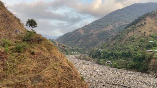 Scenic Mountain Valley View with Rocky Riverbed and Green Hills
