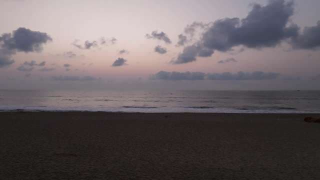 Serene Beach Sunset with Pink Sky and Calm Ocean Waves