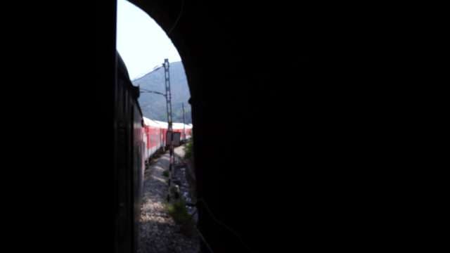 Red and White Train Emerging From Dark Mountain Tunnel