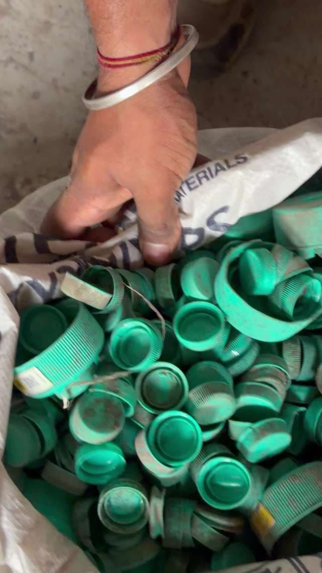 Close-Up of Hand Sorting Green Plastic Bottle Caps for Recycling
