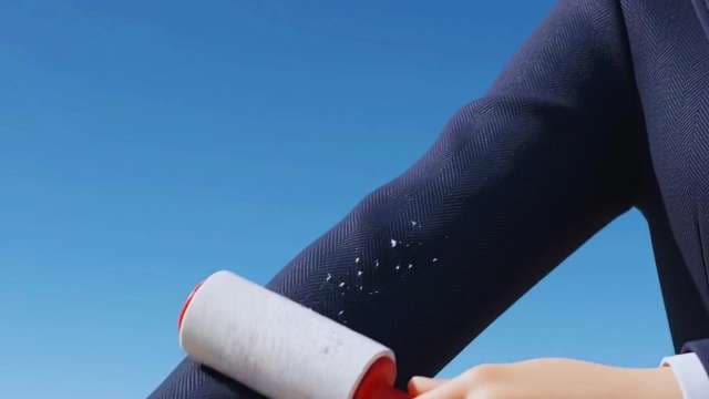 Man Using Lint Roller on Dark Business Suit Jacket