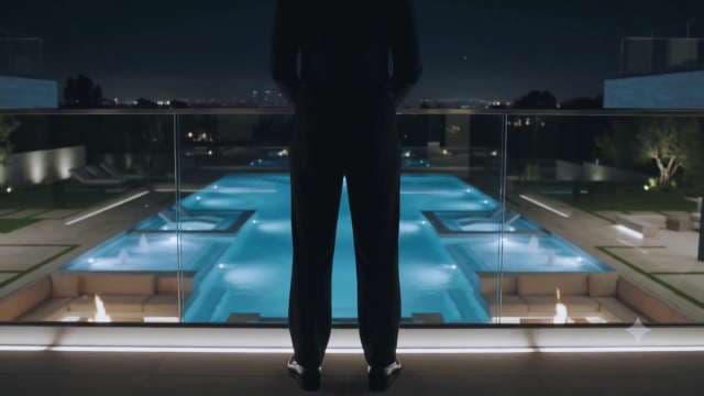 Silhouette of Man Overlooking Luxury Mansion Pool at Night