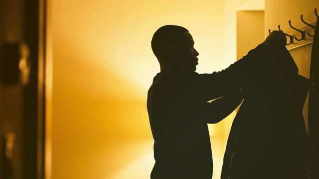 Silhouette of Man Hanging Jacket in Warm Entryway Hallway