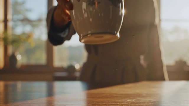 Person Placing Ceramic Coffee Cup on Table in Warm Sunlight