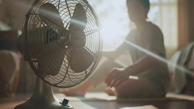Vintage Electric Fan Cooling a Person in Sunlit Room