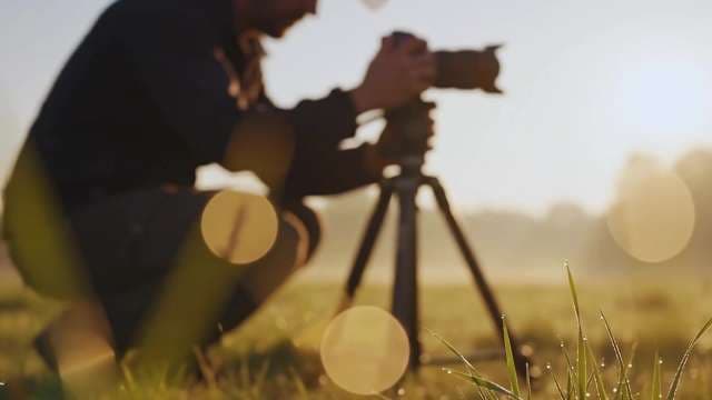 Professional Photographer Filming Nature at Sunrise in Misty Field