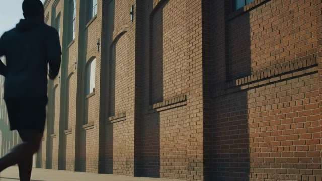 Man Jogging Past Urban Brick Building at Sunrise