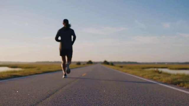 Athletic Woman Jogging on Scenic Road at Sunset