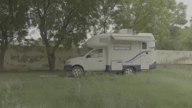 White Recreational Vehicle Parked in a Shady Green Outdoor Space
