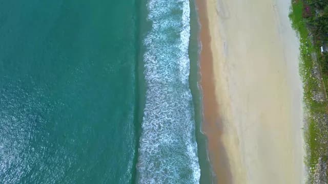 Aerial Top-Down View of Turquoise Ocean Waves Crashing on Sand in Visakhapatnam