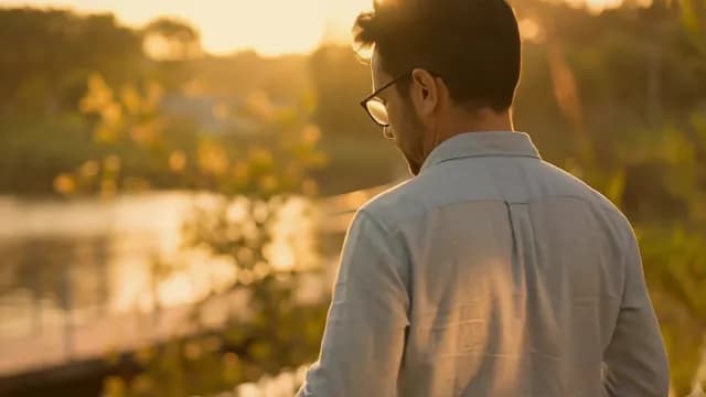 Man in Glasses Pouring Hot Drink at Golden Hour Sunset