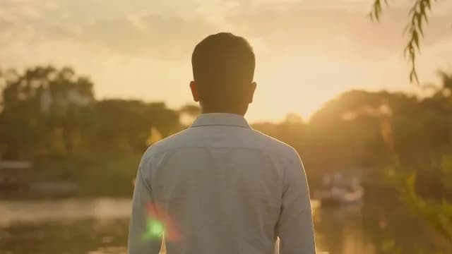 Rear View of Man Watching Golden Sunset Over Scenic River