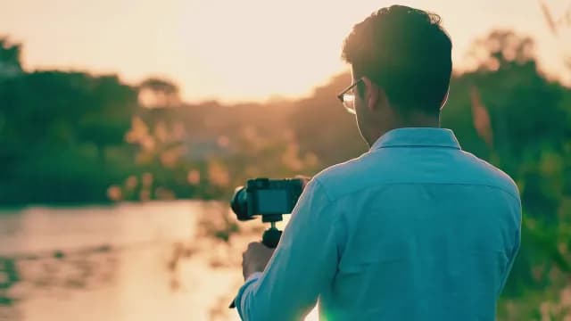 Professional Photographer Filming Scenic Lake Landscape During Golden Hour Sunset