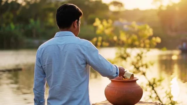 Man Pouring Water into Clay Pot at Sunset