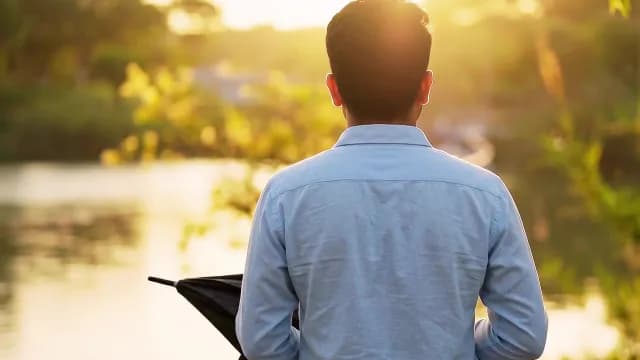 Man Standing by Lake at Golden Hour Sunset
