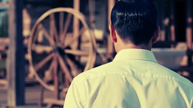 Man in White Shirt Looking at Vintage Wooden Wheel