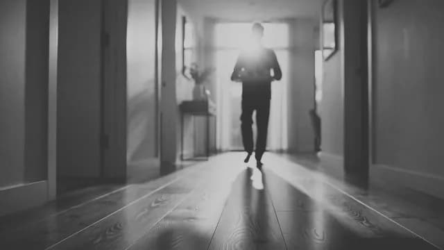 Cinematic Silhouette of Person Walking Down Modern Hallway in Black and White