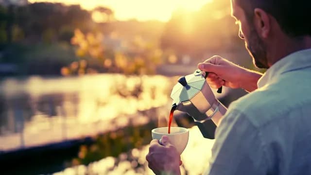 Man Pouring Fresh Coffee from Moka Pot at Golden Sunrise