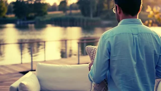 Man Relaxing on Lakeside Deck at Sunset