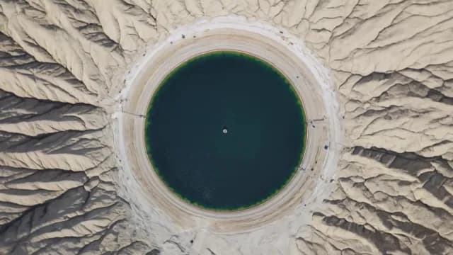 Aerial Top-Down View of Circular Turquoise Lake in Arid Badlands