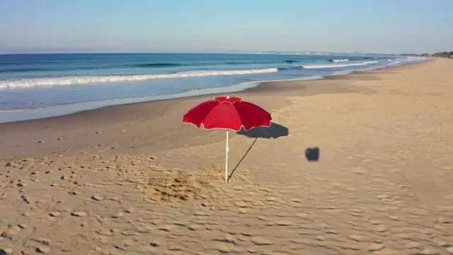 Red Beach Umbrella on Sun-Drenched Sandy Coastline