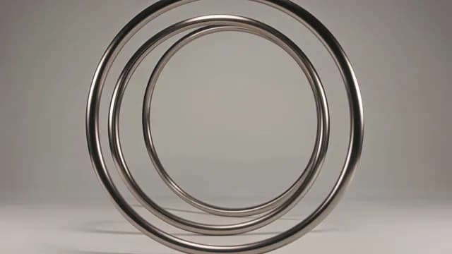 Abstract 3D Metallic Chrome Rings Rotating on Gray Background