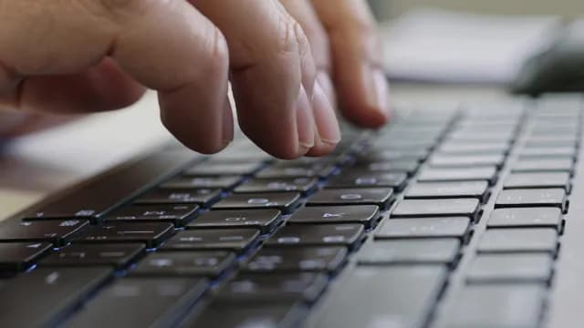 Hands Typing on Backlit Computer Keyboard