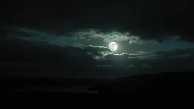 Full Moon Shining Through Dark Clouds Over Night Landscape