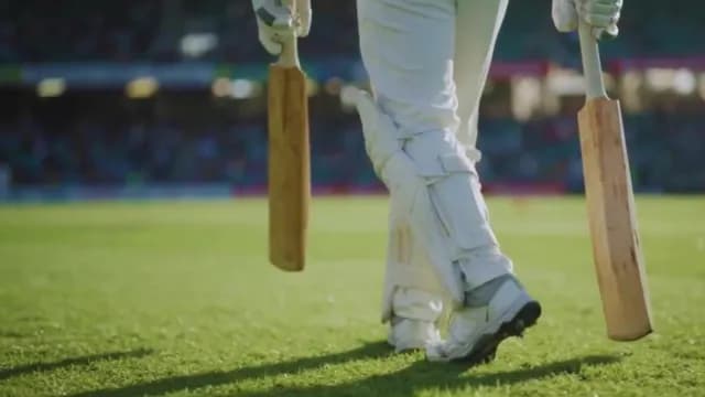 Cricket Player Walking on Field with Bats