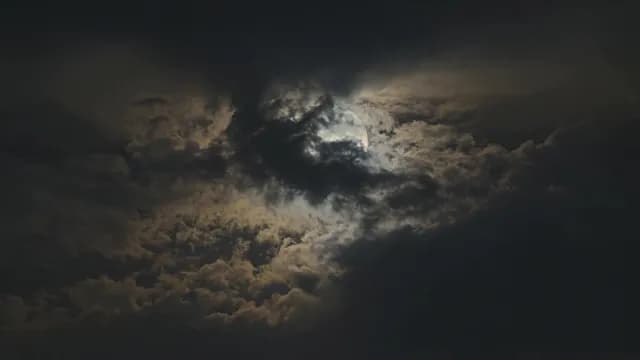 Dramatic Full Moon Peeking Through Dark Clouds at Night