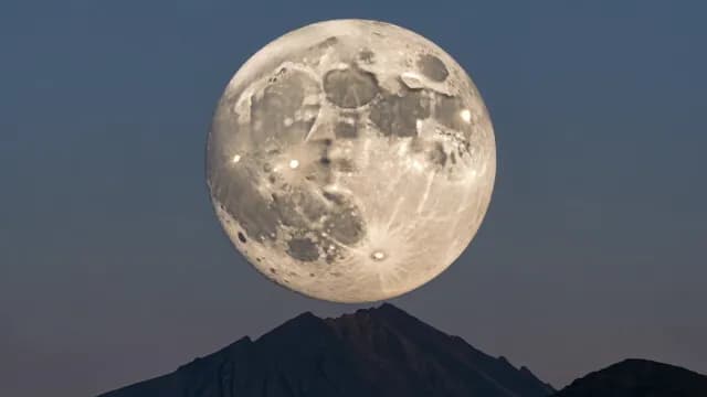 Supermoon Rising Directly Over Rugged Mountain Peak at Night