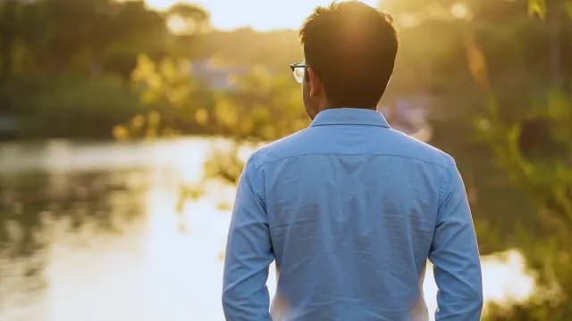 Man Contemplating by a Serene Lake at Sunset Golden Hour