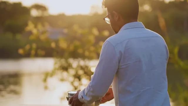Man Carrying Tiffin Container Near Lake During Golden Hour Sunset