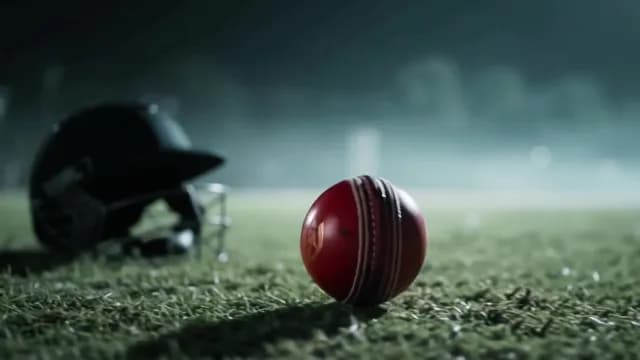 Red Cricket Ball on Grass Pitch Under Night Stadium Lights