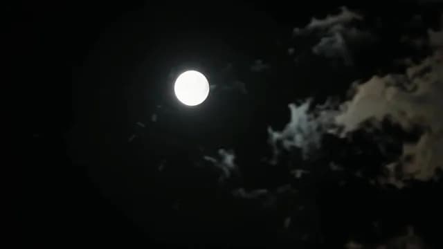 Bright Full Moon Shining Through Eerie Clouds in a Dark Night Sky