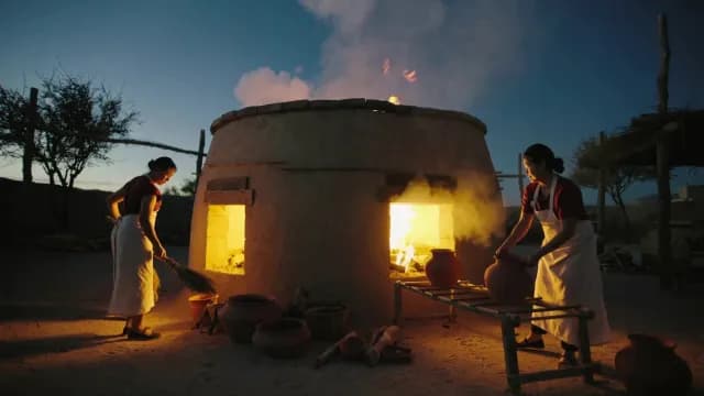 Traditional Artisans Firing Earthenware Pots in Large Outdoor Kiln at Dusk
