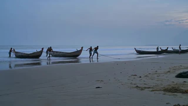 Local Fishermen Pulling Traditional Wooden Boats Ashore at Dawn