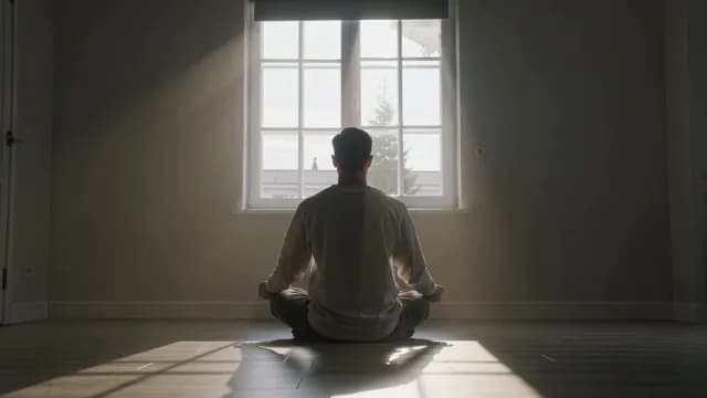 Man Meditating in Front of Window with Dramatic Sunlight Rays