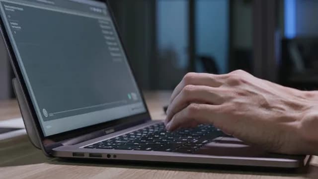 Close-up of Hands Typing on a Laptop Keyboard in Dim Lighting